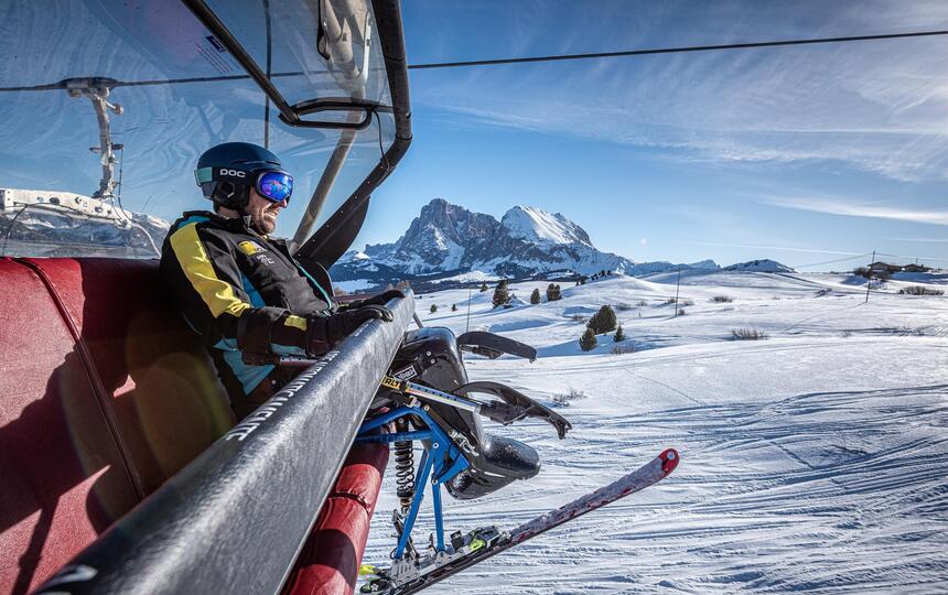 Ein Mann mit Monoski fährt mit dem Sessellift