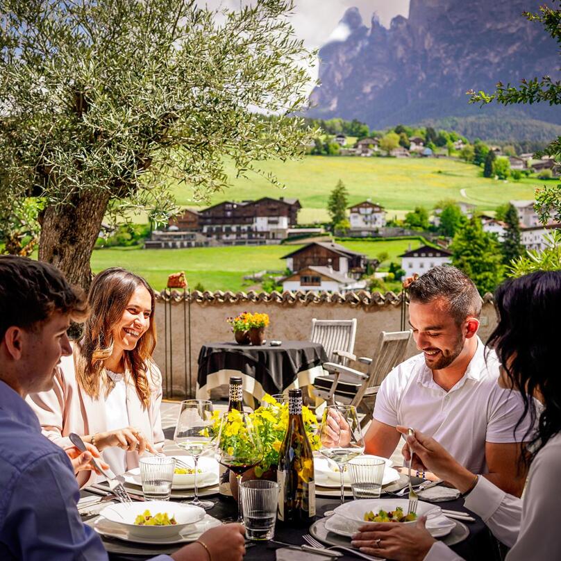 Vier Personen sitzen gemeinsam am Tisch und genießen verschiedene Südtiroler Gerichte