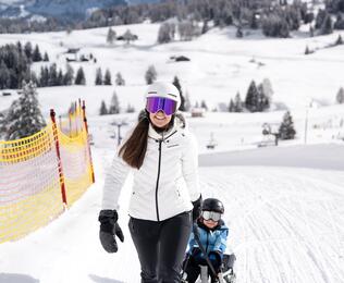 Eine Frau zieht ein Kind auf einer Rodel