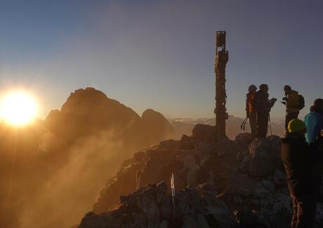 Tre persone stanno su una vetta all’alba