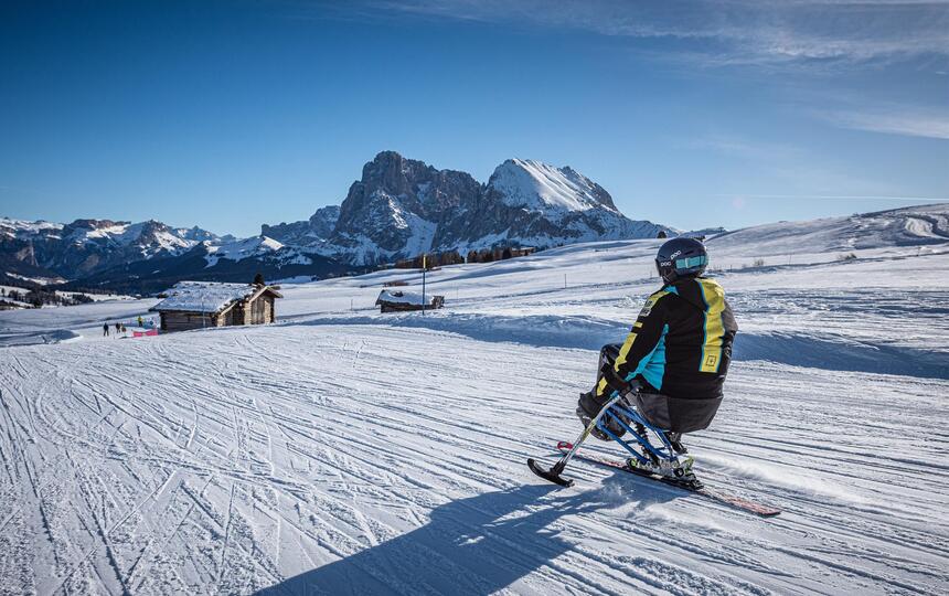 Ein Mann mit Monoski fährt eine Skipiste hinab