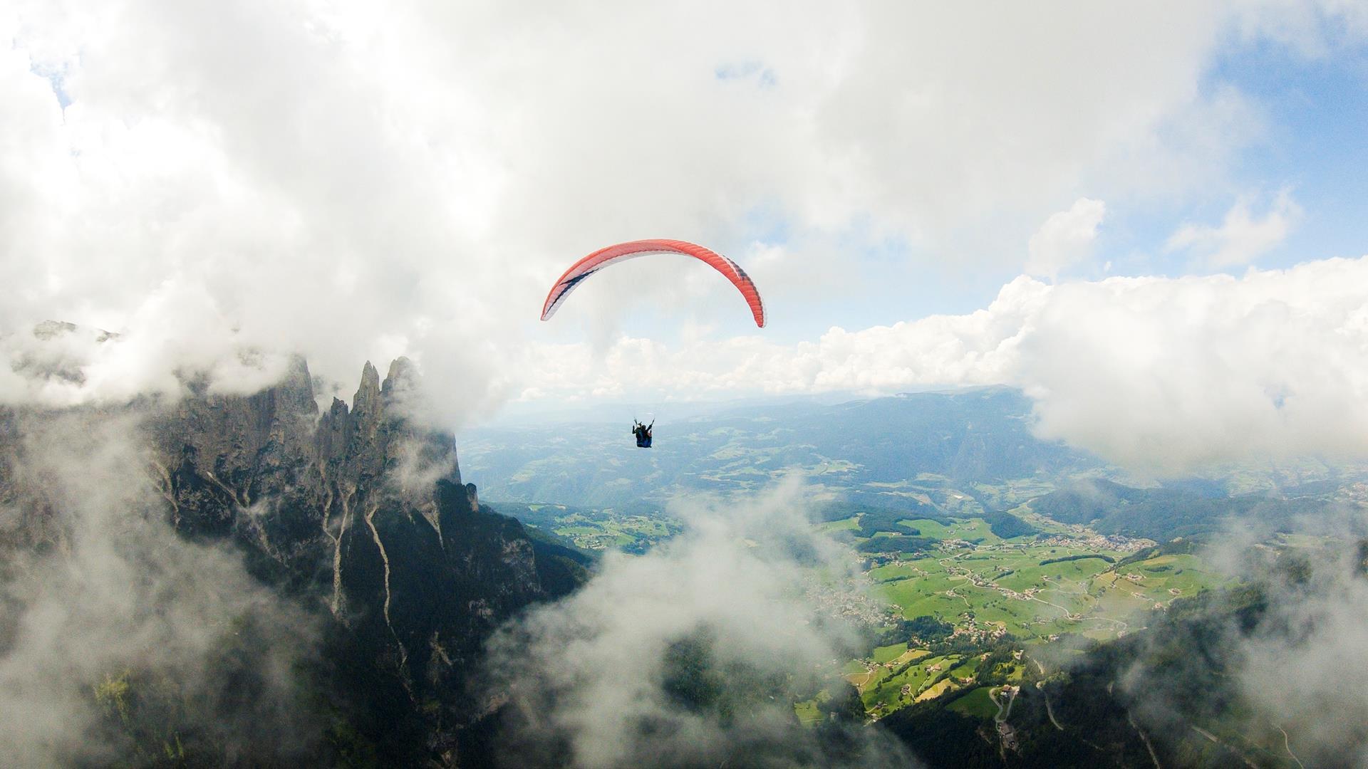 Eine Person beim Paragliden, im Hintergrund erhebt sich der Schlern