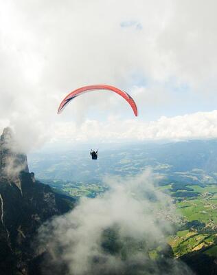 Eine Person beim Paragliden, im Hintergrund erhebt sich der Schlern