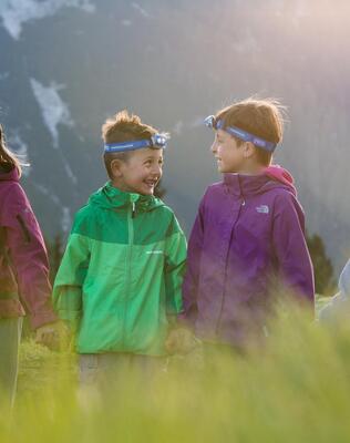Quattro bambini si tengono per mano e scoprono la natura con le lampade frontali