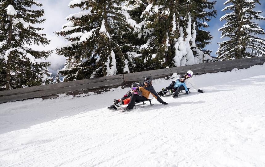Eine Familie mit zwei Kindern rodelt