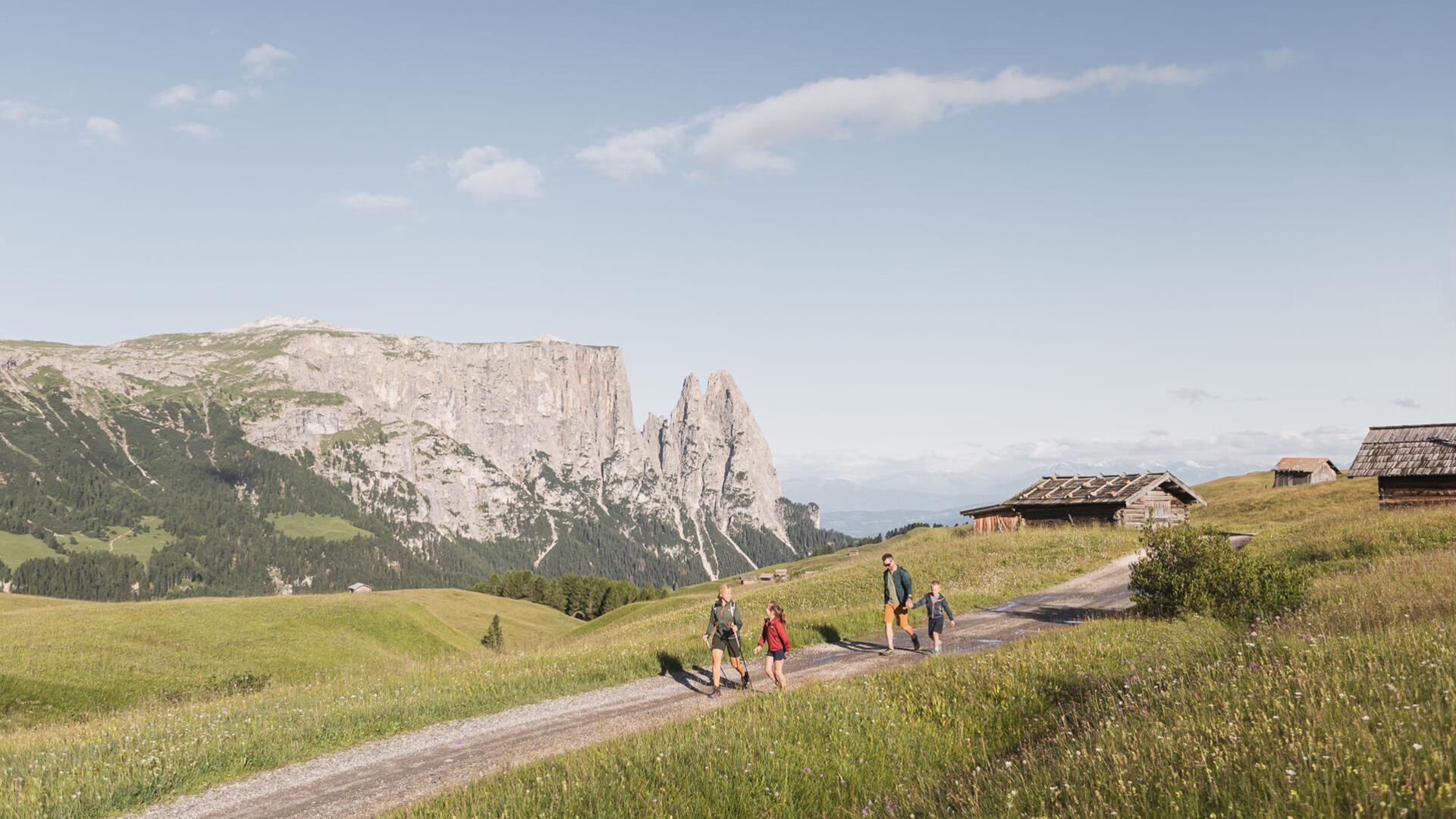 Eine Familie mit zwei Kindern wandert, im Hintergrund der Schlern