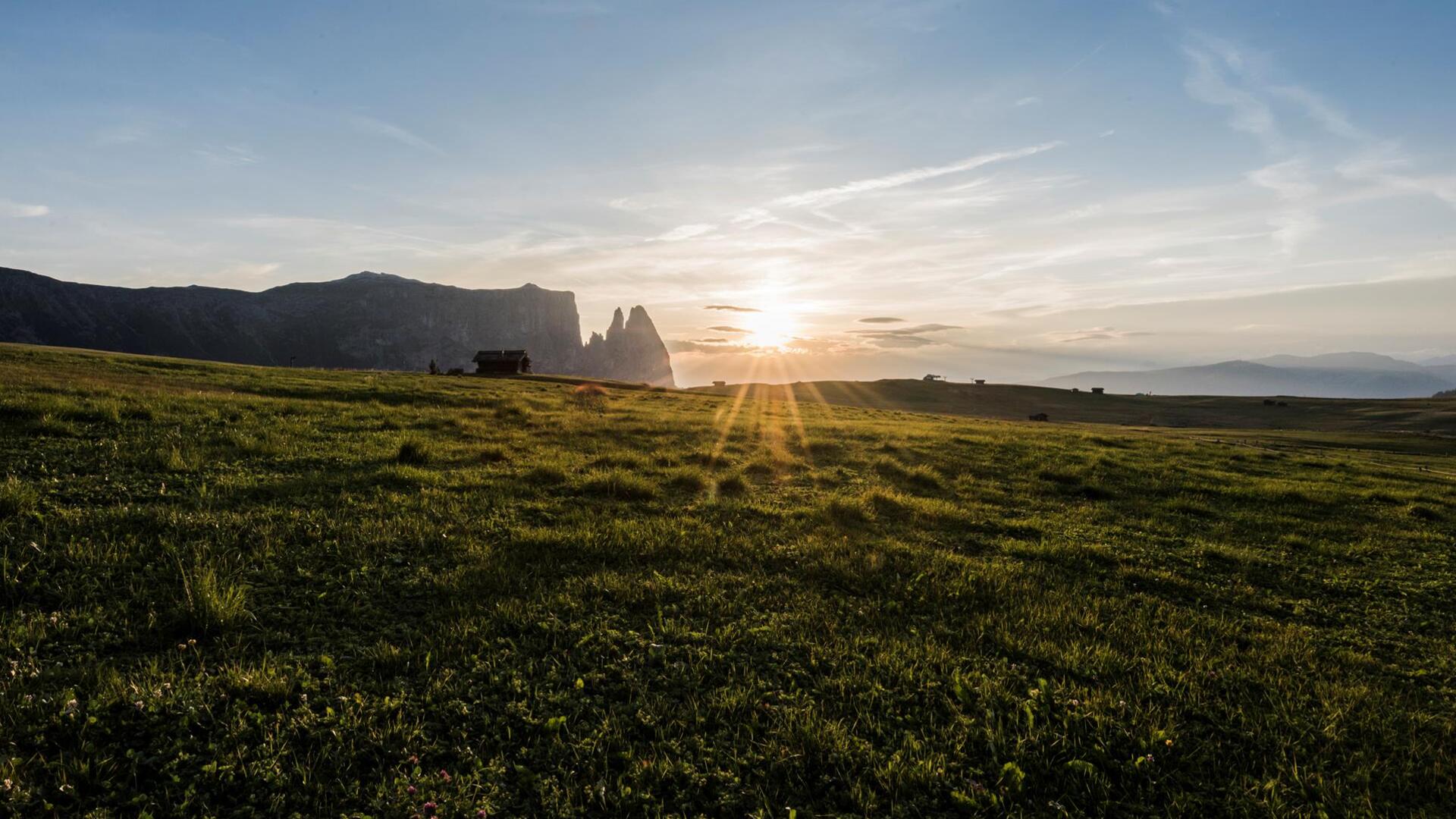 Tramonto sull’Alpe di Siusi con ampi prati e montagne nella luce calda