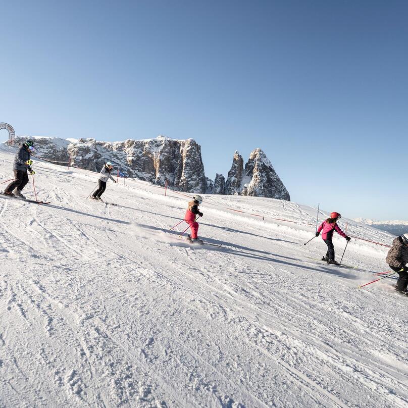 A family is skiing, with the Schlern mountain in the background