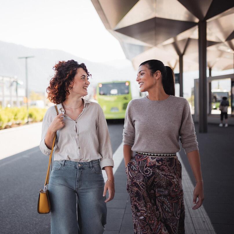 Zwei Frauen an einem Busbahnhof