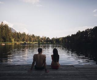 Ein Mann und eine Frau sitzen auf einem Steg am Völser Weiher