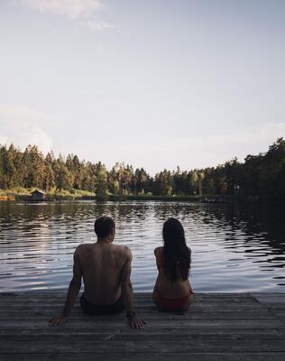 Ein Mann und eine Frau sitzen auf einem Steg am Völser Weiher
