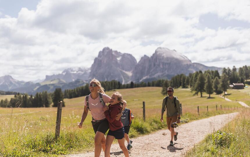 Eine Familie mit zwei Kindern wandert auf der Seiser Alm, im HIntergrund der Schlern