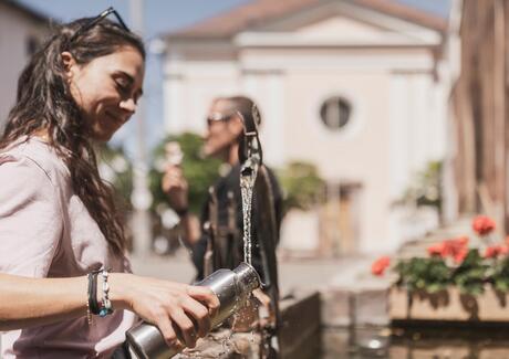 A woman is filling a water bottle at a fountain