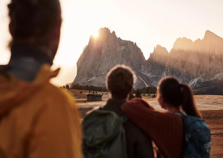Due uomini e una donna guardano le Dolomiti alla luce della sera