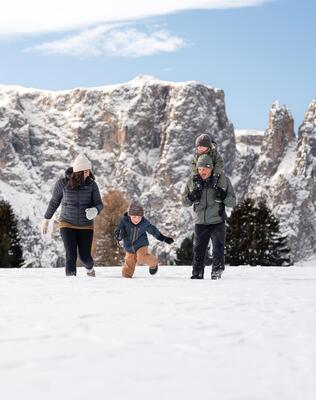 Eine Familie mit zwei Kinder stapft durch den Schnee