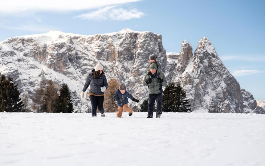 Eine Familie mit zwei Kinder stapft durch den Schnee