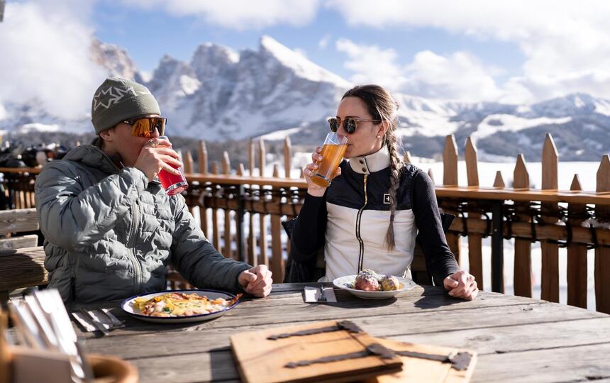 Ein Mann und eine Frau trinken Saft und genießen ein Südtiroler Gericht