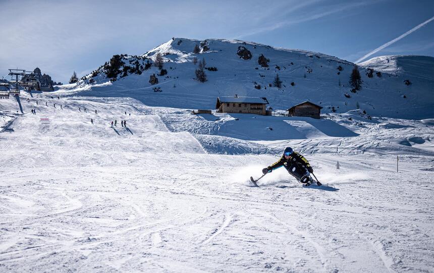 Ein Mann mit Monoski fährt eine Skipiste hinab