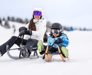 Eine Frau mit einem Kind beim Rodeln