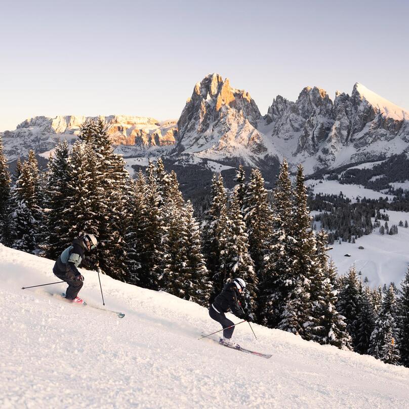 Ein Mann und eine Frau fahren eine Skipiste hinunter