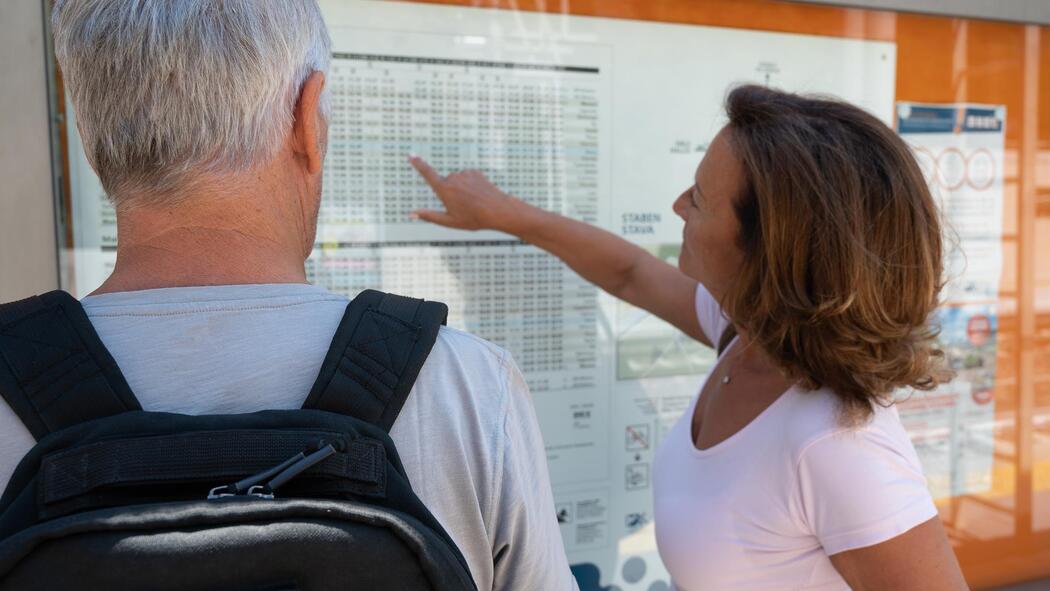 Ein Mann und eine Frau lesen einen Busfahrplan