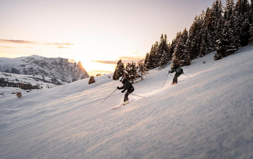 Ein Mann und eine Frau fahren eine Skipiste hinunter