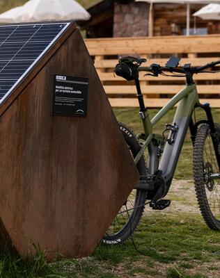Ein E-bike lädt an einer mobilen Zapfsäule vor einer Almhütte