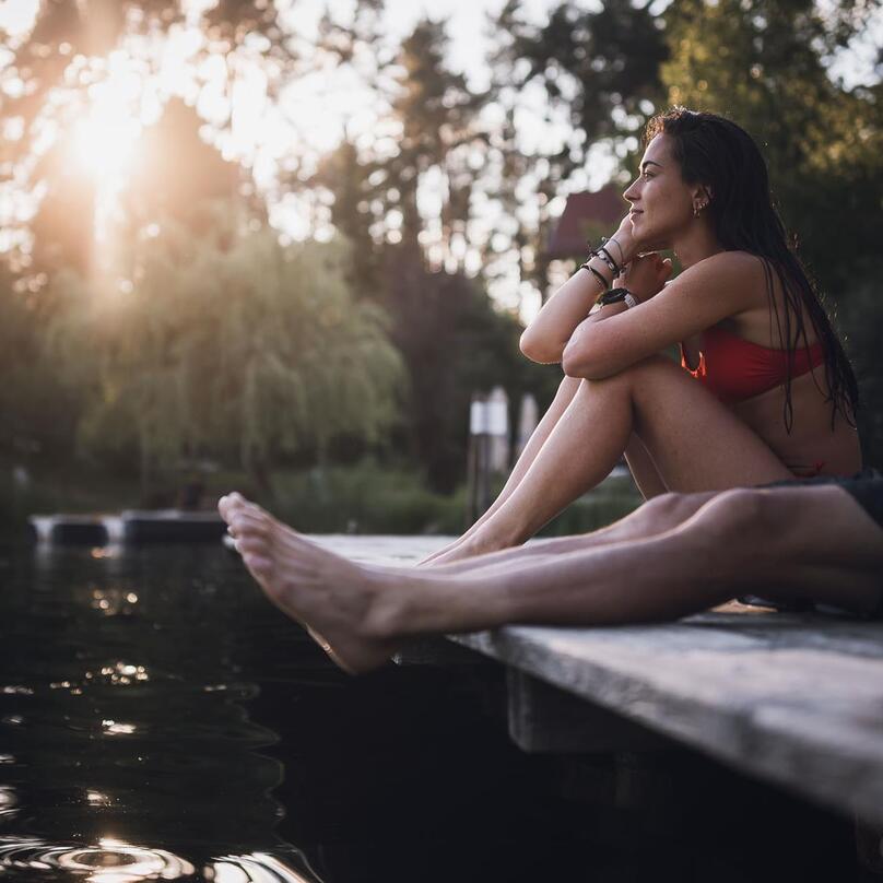 Ein Mann und eine Frau sitzen auf einem Steg am Völser Weiher